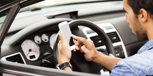 Young man using smart phone in his car